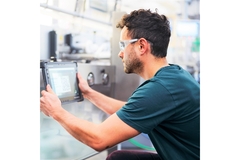 Image A man in a green shirt using a tablet in production